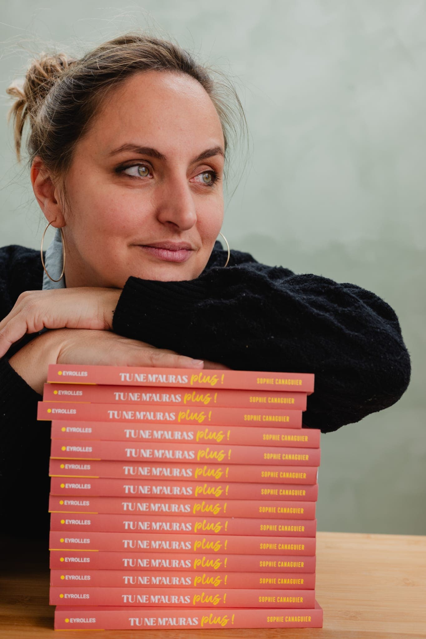 Sophie Canaguier, thérapeute psycho-corporelle, accoudée à une pile de son livre Tu ne m’auras plus !